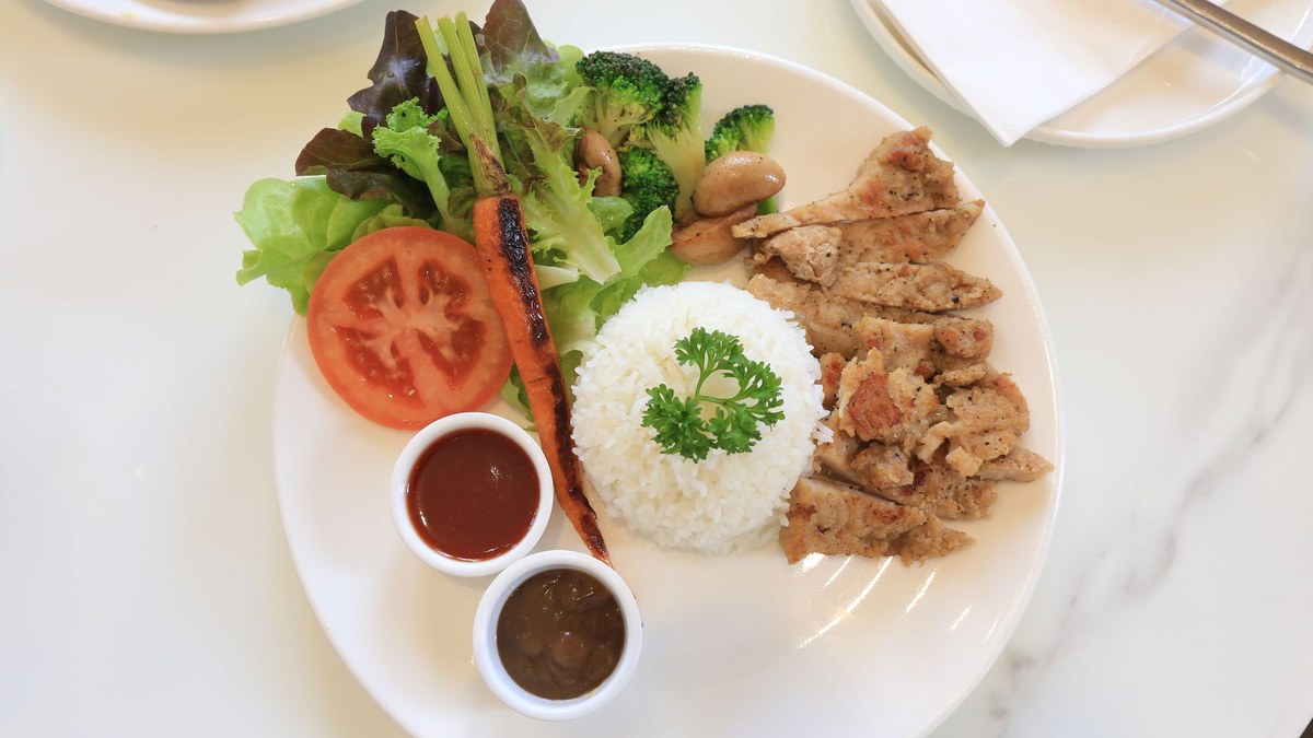 Assiette de poulet grillé, oeufs durs, riz complet et brocolis sur plan de travail en bois