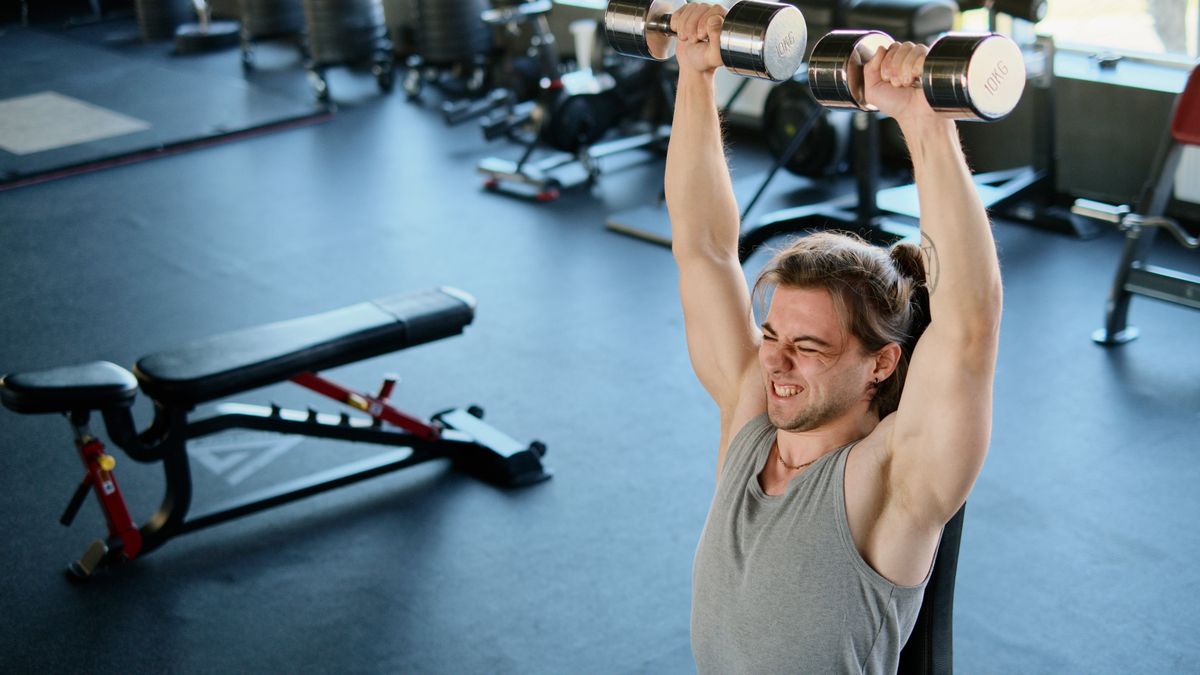 Sportif en séance de développé couché haltères sur banc dans un home gym lumineux