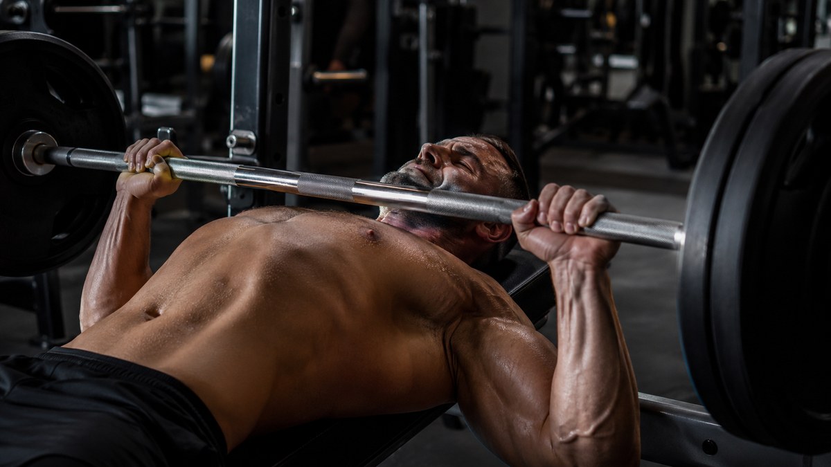 Sportif en pleine séance de développé couché en salle de sport, structure push pull legs