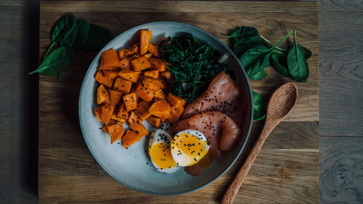 Bol composé de saumon, patate douce rôtie, épinards et œuf mollet, repas post-entraînement